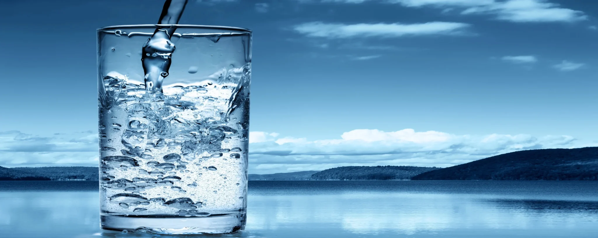 A glass of clean drinking water beside a lake